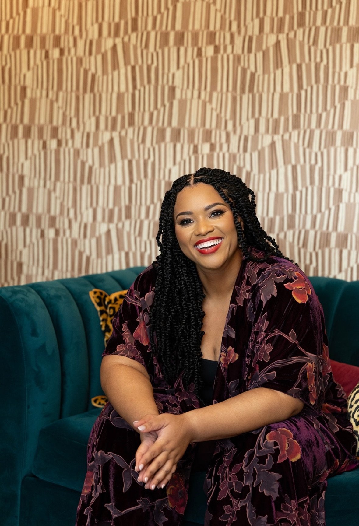 Dr. Monica Johnson, founder and psychologist at Kind Mind Psychology, seated on a teal couch smiling