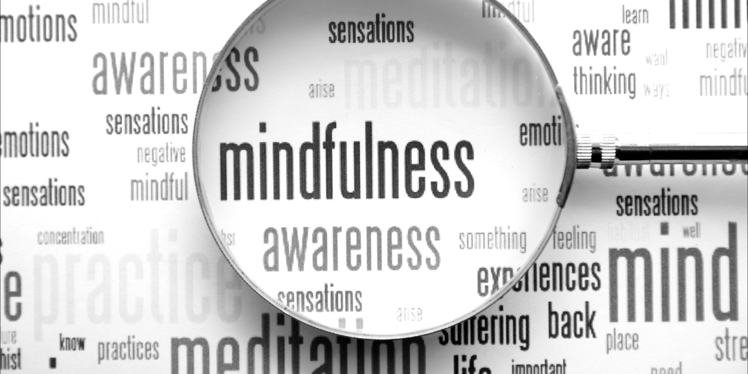 Magnifying glass over the word mindfulness in a collage of related words