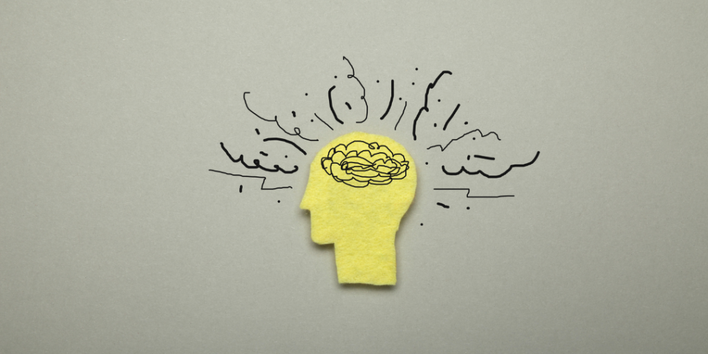Yellow felt head cutout with a scribbled brain and jagged lines, representing ADHD and anxiety