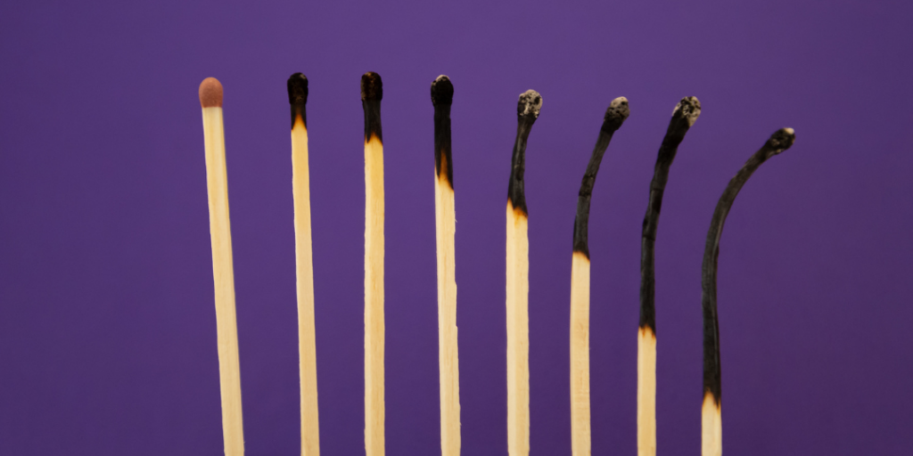 Row of matchsticks from unburned to burnt on a purple background, representing ADHD burnout