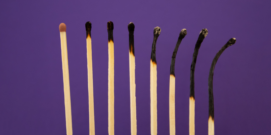 Row of matchsticks from unburned to burnt on a purple background, representing ADHD burnout