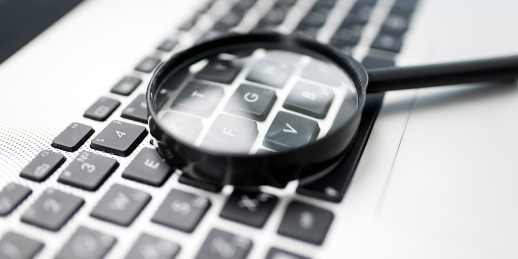 Magnifying glass over a laptop keyboard, representing searching for an IFS therapist in NYC